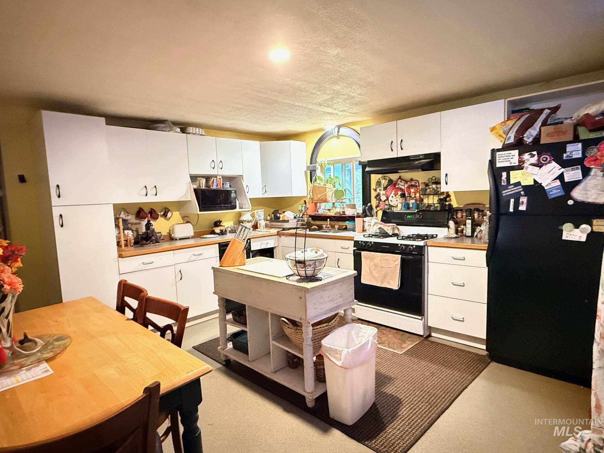 5742 Grangemont Road Orofino, ID 83544 - Photo 6 of 25 Kitchen featuring white cabinetry, wood-finish countertops, black appliances, a built-in microwave, and an arched window