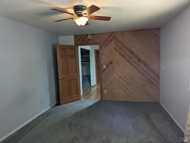 an empty room with closet and a chandelier fan