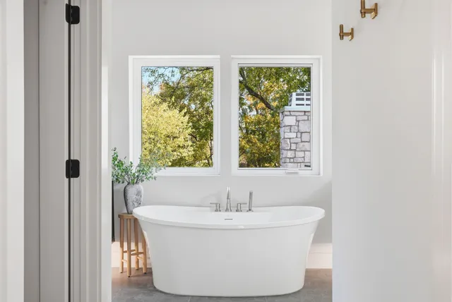 a white bath tub sitting in a bathroom next to a window