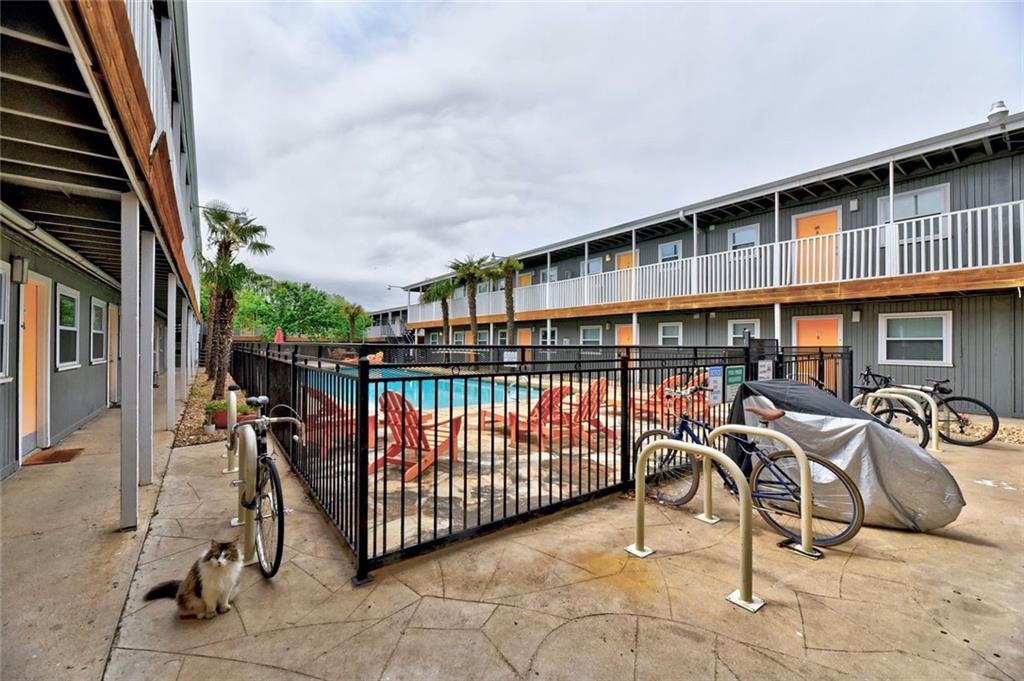 2401 Manor Road, Unit 221 Austin, TX 78722 - Photo 18 of 21 A refreshing pool awaits, encircled by apartment units featuring private balconies and tropical landscaping.