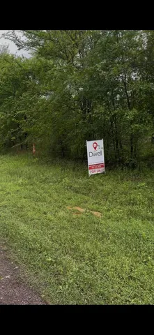 a sign that is sitting in front of a tree