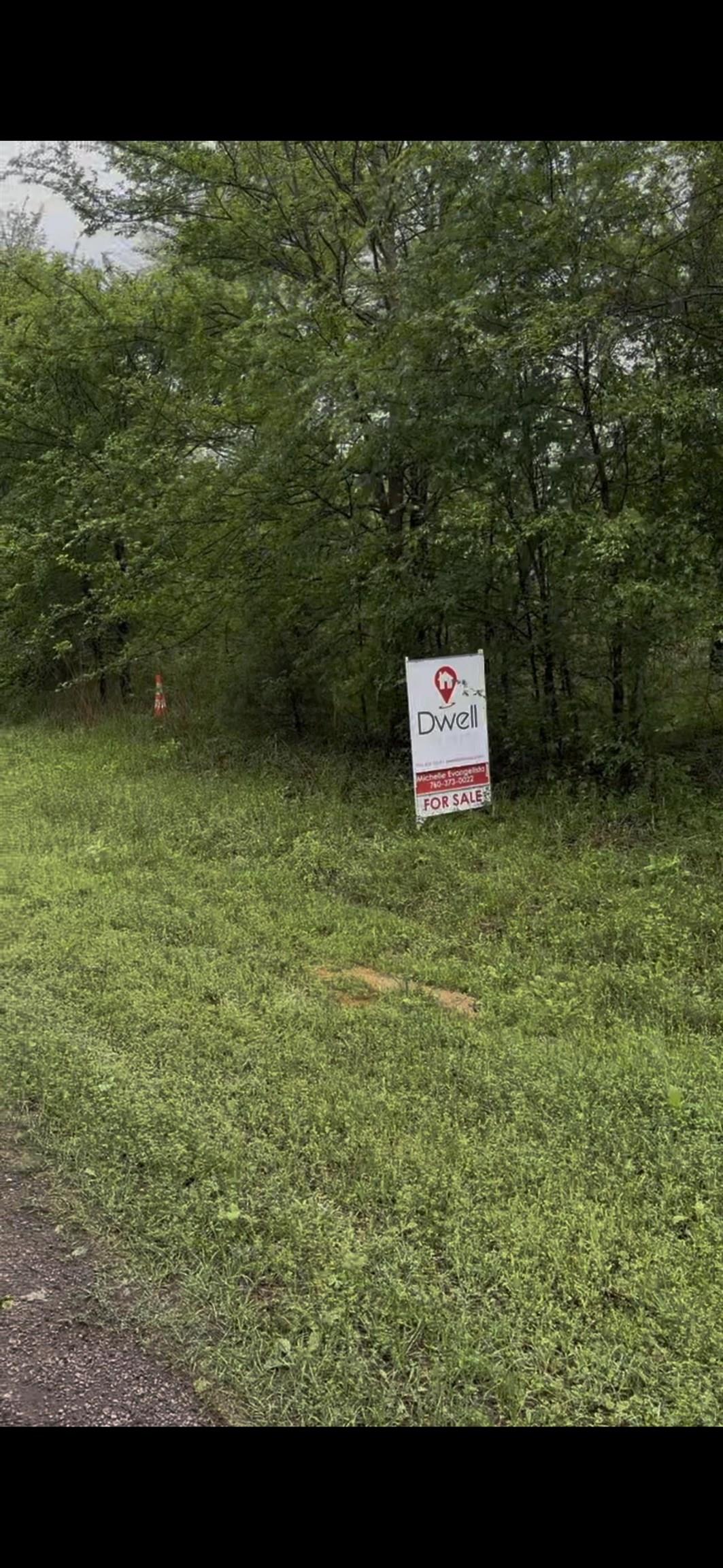 a sign that is sitting in front of a tree