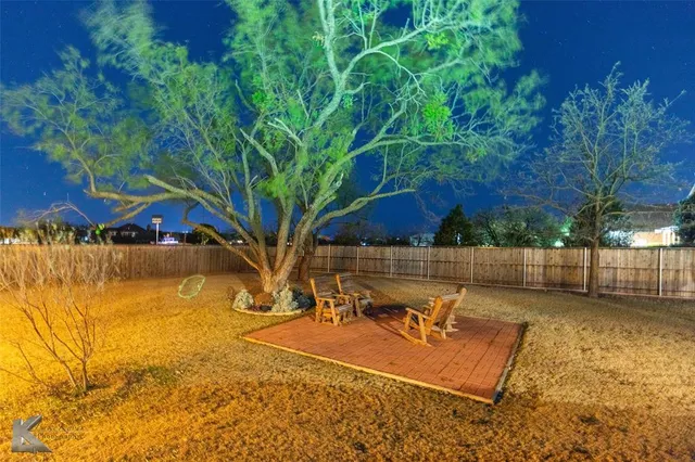 a view of a yard with a table and chair under an umbrella
