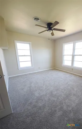 an empty room with windows and ceiling fan