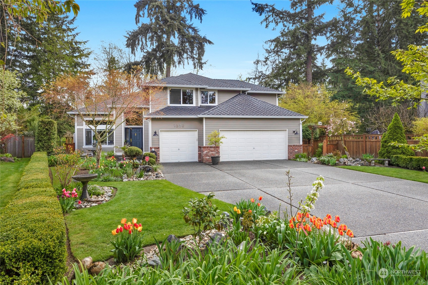 a front view of a house with a garden and trees