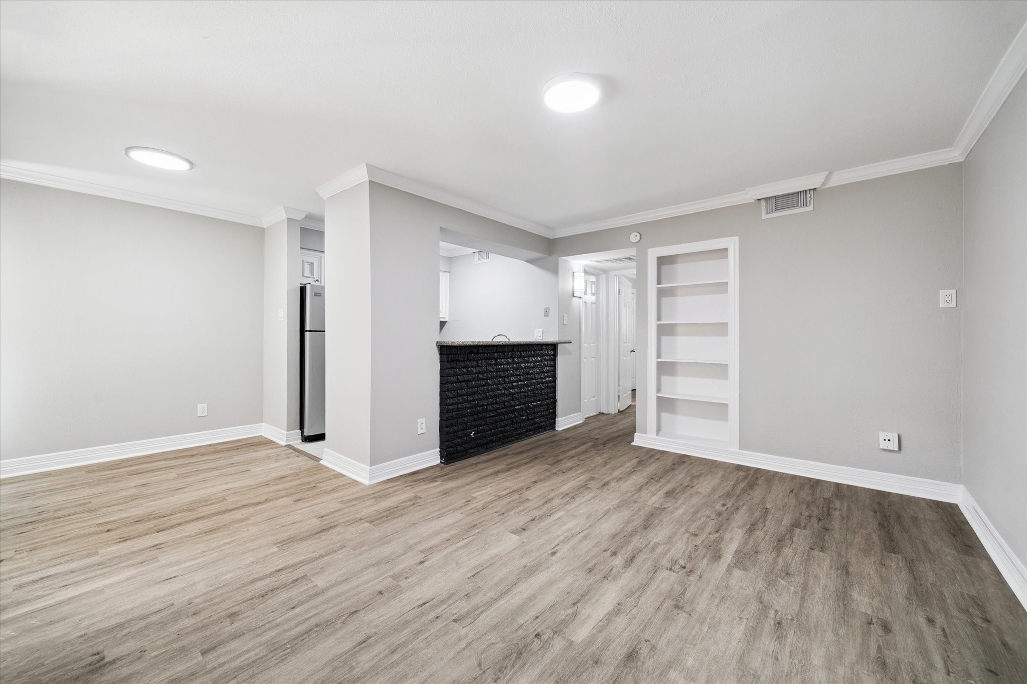 a view of an empty room with wooden floor closet and windows