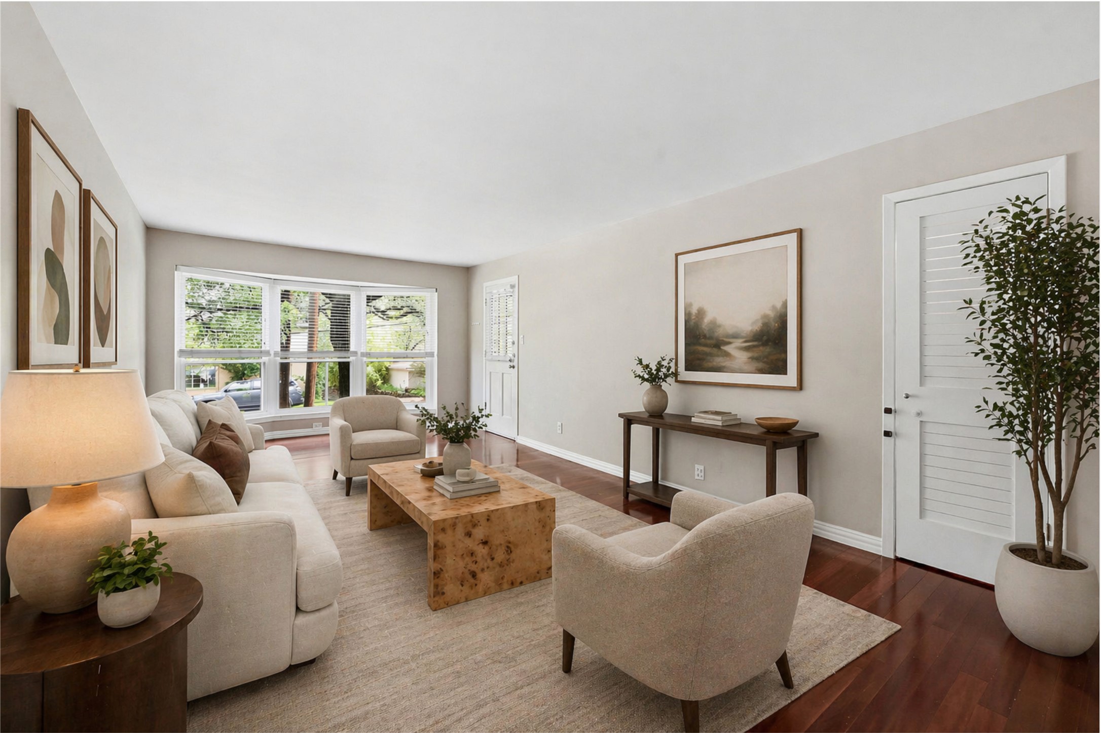 Spacious living area featuring rich wood-finish flooring, a large picture window, and light-toned walls