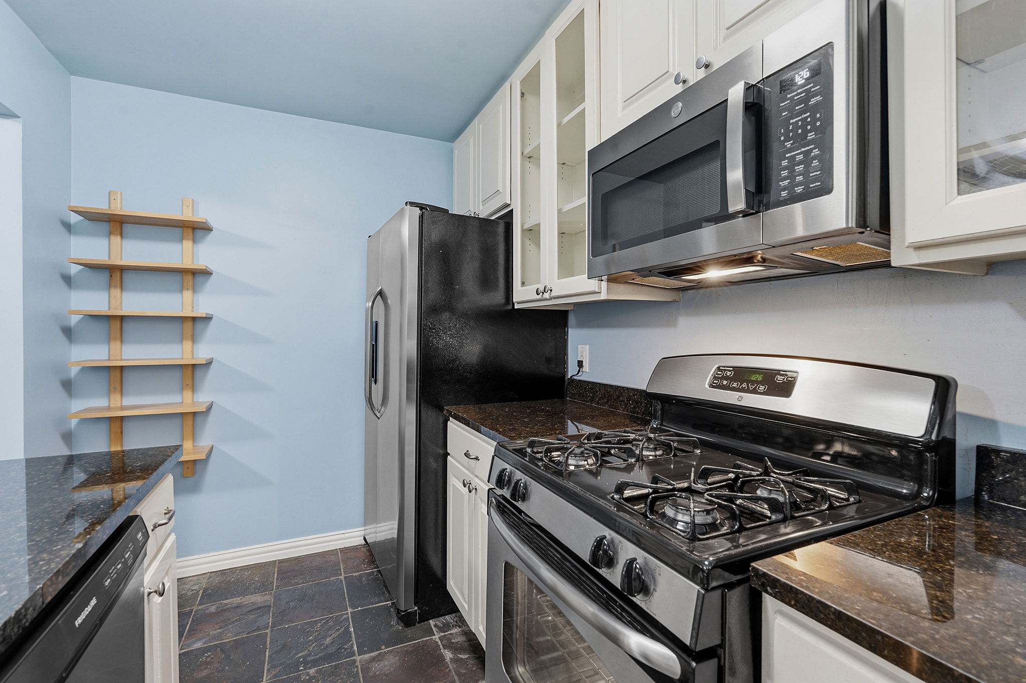 1210 Windsor Road, Unit 104 Austin, TX 78703 - Photo 11 of 27 Kitchen featuring stainless steel appliances, dark stone countertops, white shaker-style cabinetry, and slate-finish floor tile
