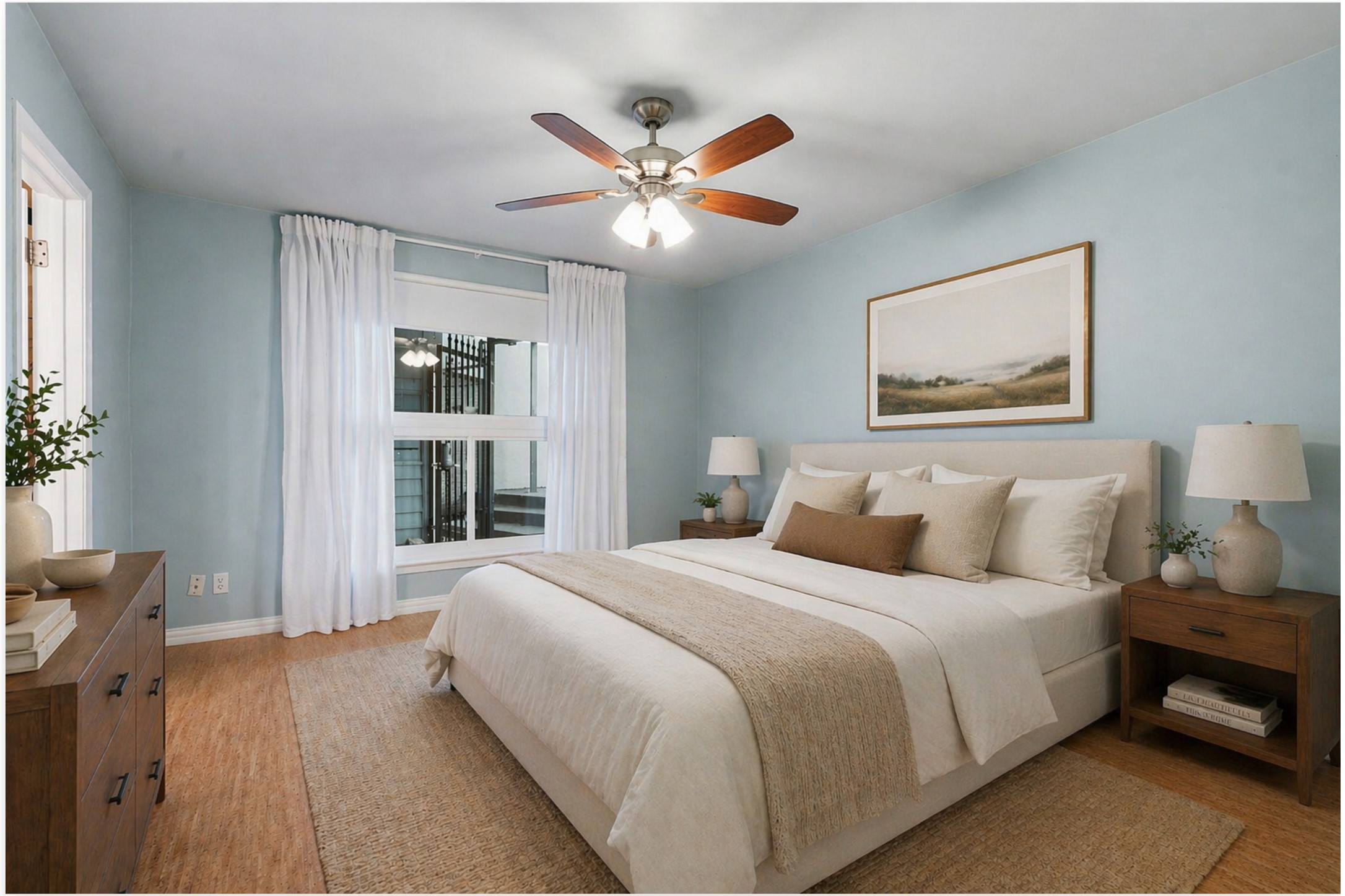 1210 Windsor Road, Unit 104 Austin, TX 78703 - Photo 14 of 27 Spacious bedroom featuring light blue walls, wood-finish flooring, a ceiling fan with integrated lighting, and a large window with white drapery