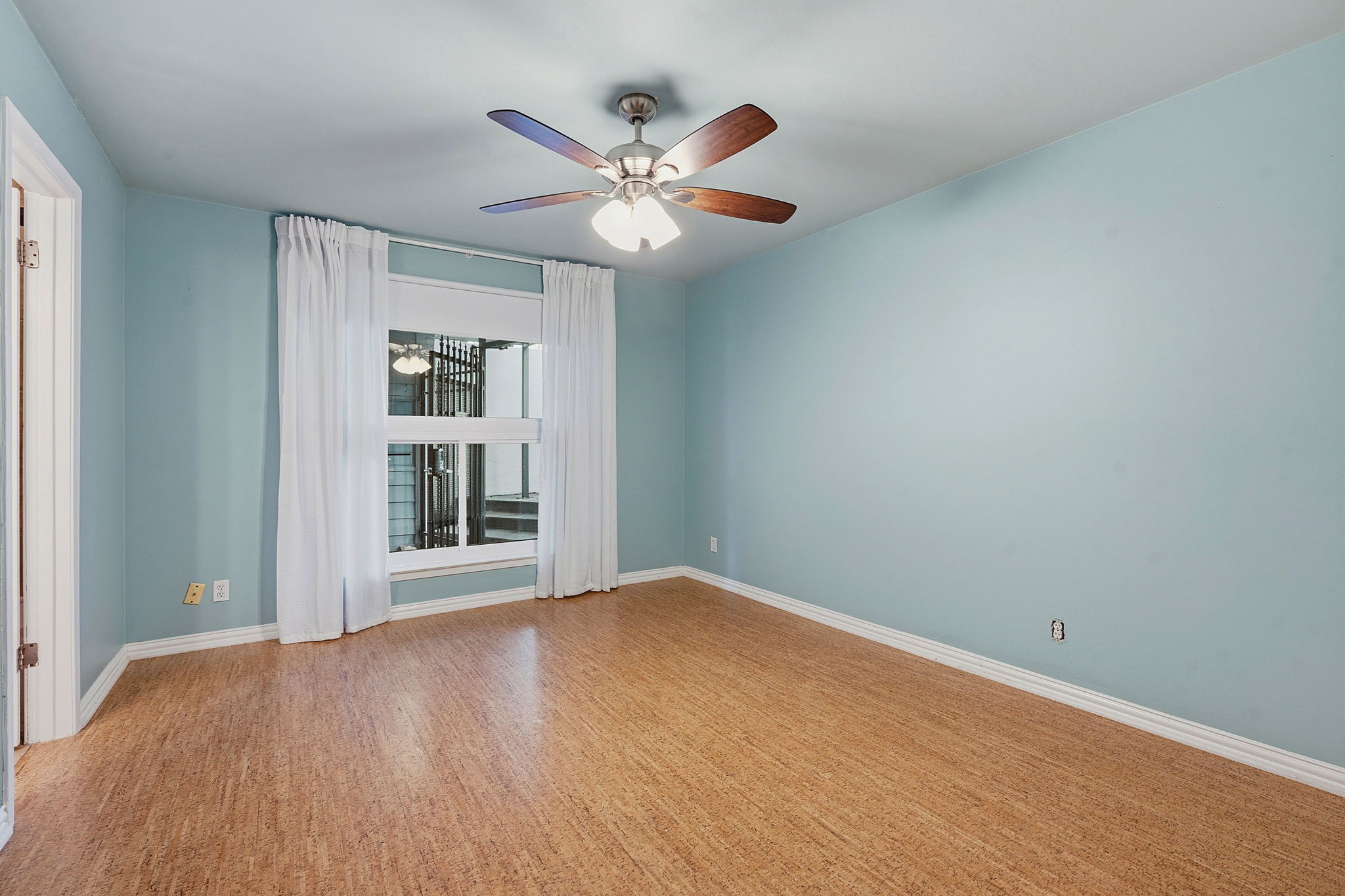 1210 Windsor Road, Unit 104 Austin, TX 78703 - Photo 15 of 27 Room with wood-finish flooring, a ceiling fan with light fixture, and a window with white trim