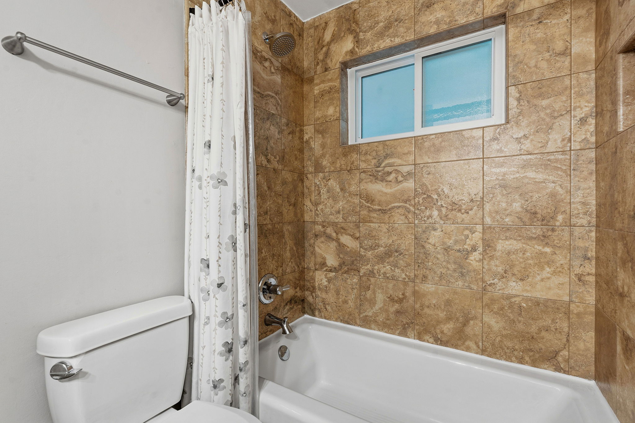 1210 Windsor Road, Unit 104 Austin, TX 78703 - Photo 18 of 27 White bathtub featuring a tiled surround with an integrated window, a showerhead, and chrome fixtures