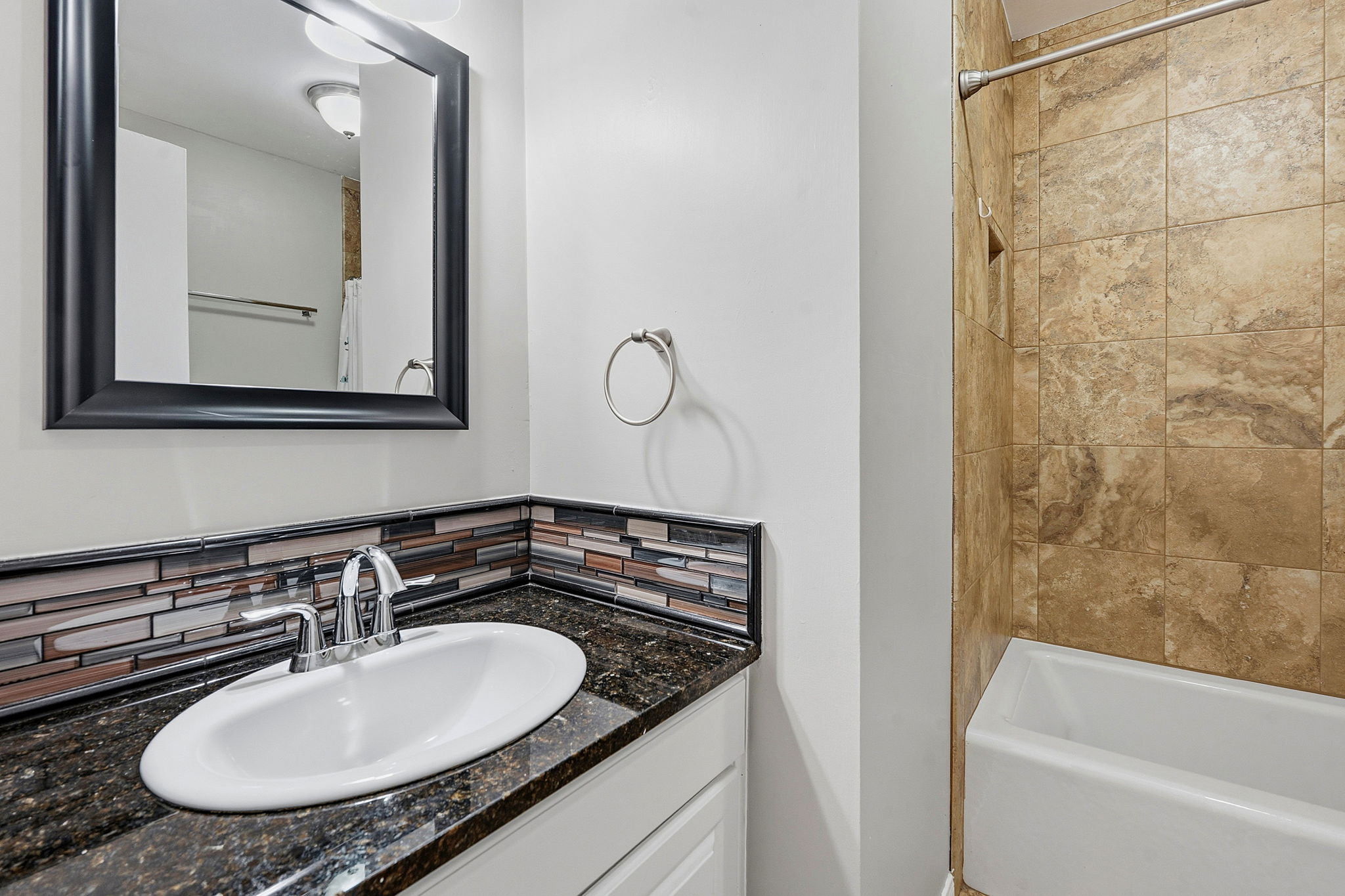 1210 Windsor Road, Unit 104 Austin, TX 78703 - Photo 21 of 27 Bathroom featuring a vanity with an undermount sink, a dark speckled countertop, and a mosaic tile backsplash