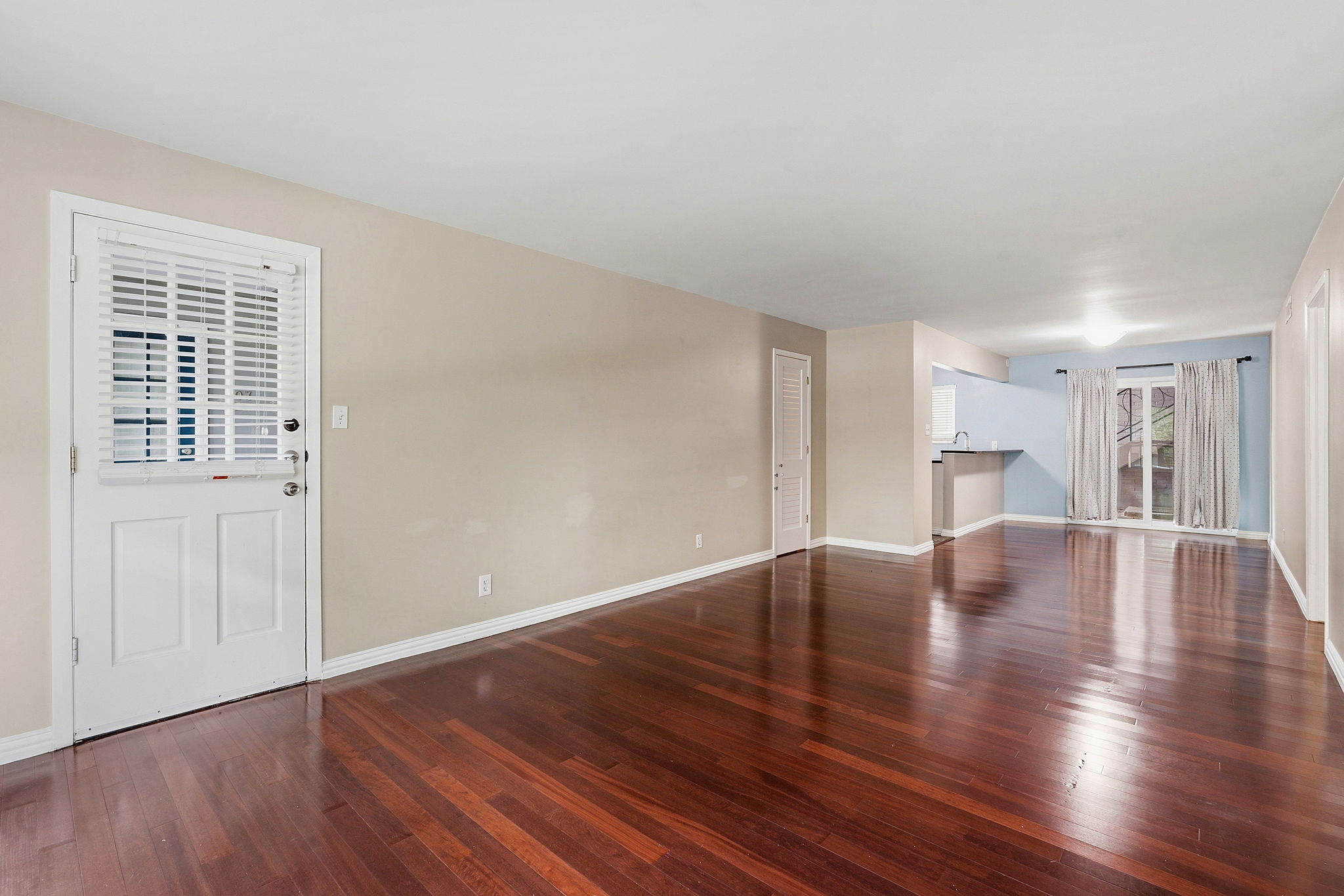 1210 Windsor Road, Unit 104 Austin, TX 78703 - Photo 6 of 27 Spacious living area featuring rich wood-finish flooring, neutral wall tones, a white entry door with integrated blinds, and recessed lighting