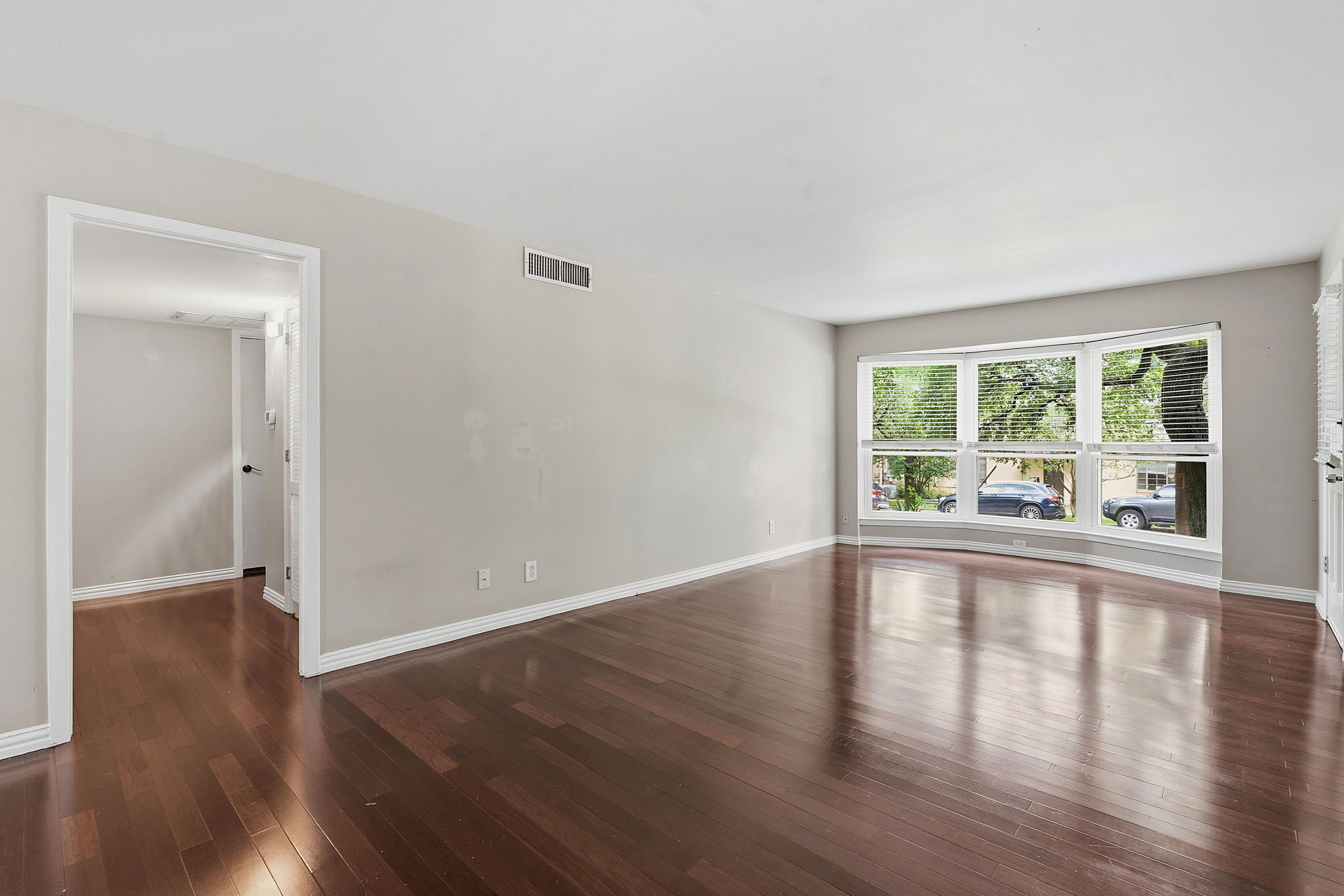 1210 Windsor Road, Unit 104 Austin, TX 78703 - Photo 7 of 27 Spacious room featuring wood-finish flooring, a large bay window, neutral wall tones, and white trim