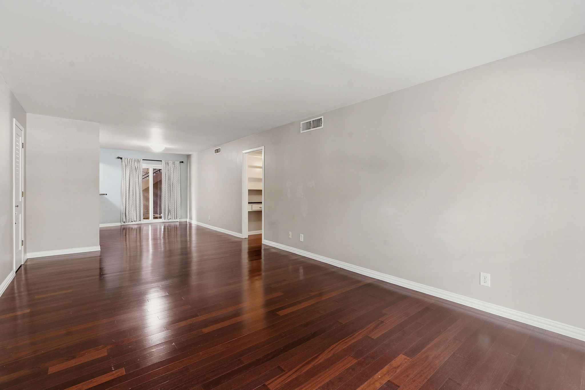 1210 Windsor Road, Unit 104 Austin, TX 78703 - Photo 8 of 27 Spacious room featuring rich wood-finish flooring, light-toned walls, white baseboards, and a bright ceiling