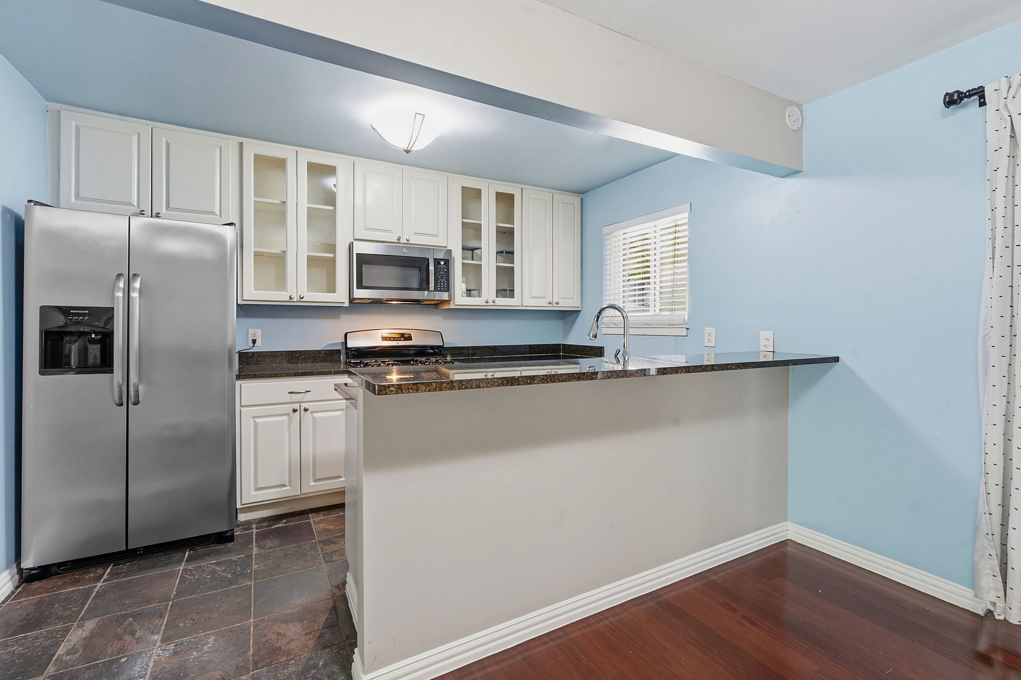 1210 Windsor Road, Unit 104 Austin, TX 78703 - Photo 9 of 27 Kitchen featuring white cabinetry with glass-front accents, stainless steel appliances, and dark countertops