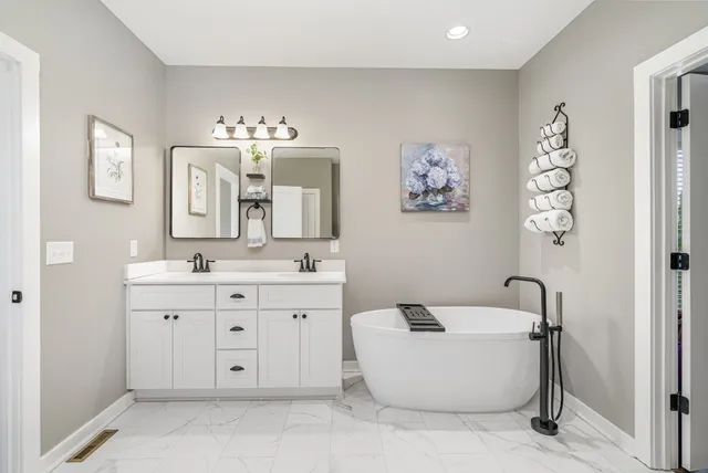 a spacious bathroom with a tub sink and mirror
