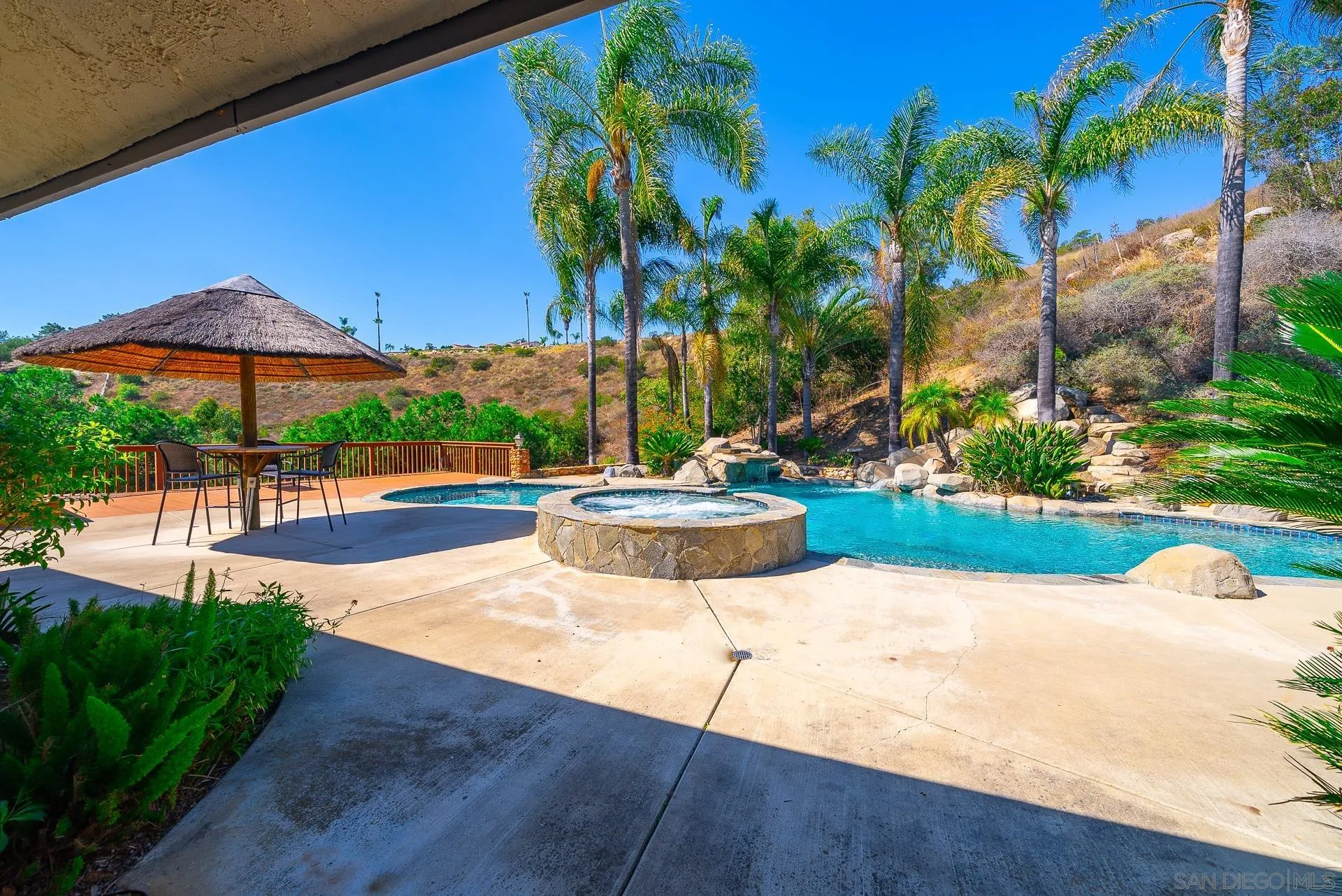 14574 Millards Road Poway, CA 92064 - Photo 61 of 75 a view of a swimming pool with a table and chairs under an umbrella