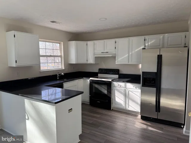 a kitchen with granite countertop stainless steel appliances a sink stove and refrigerator