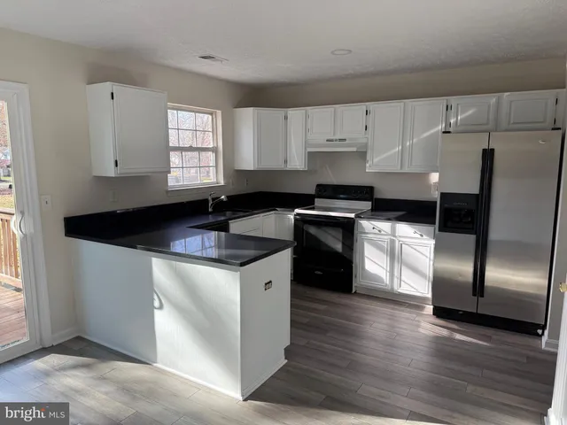 a kitchen with granite countertop a sink cabinets and stainless steel appliances