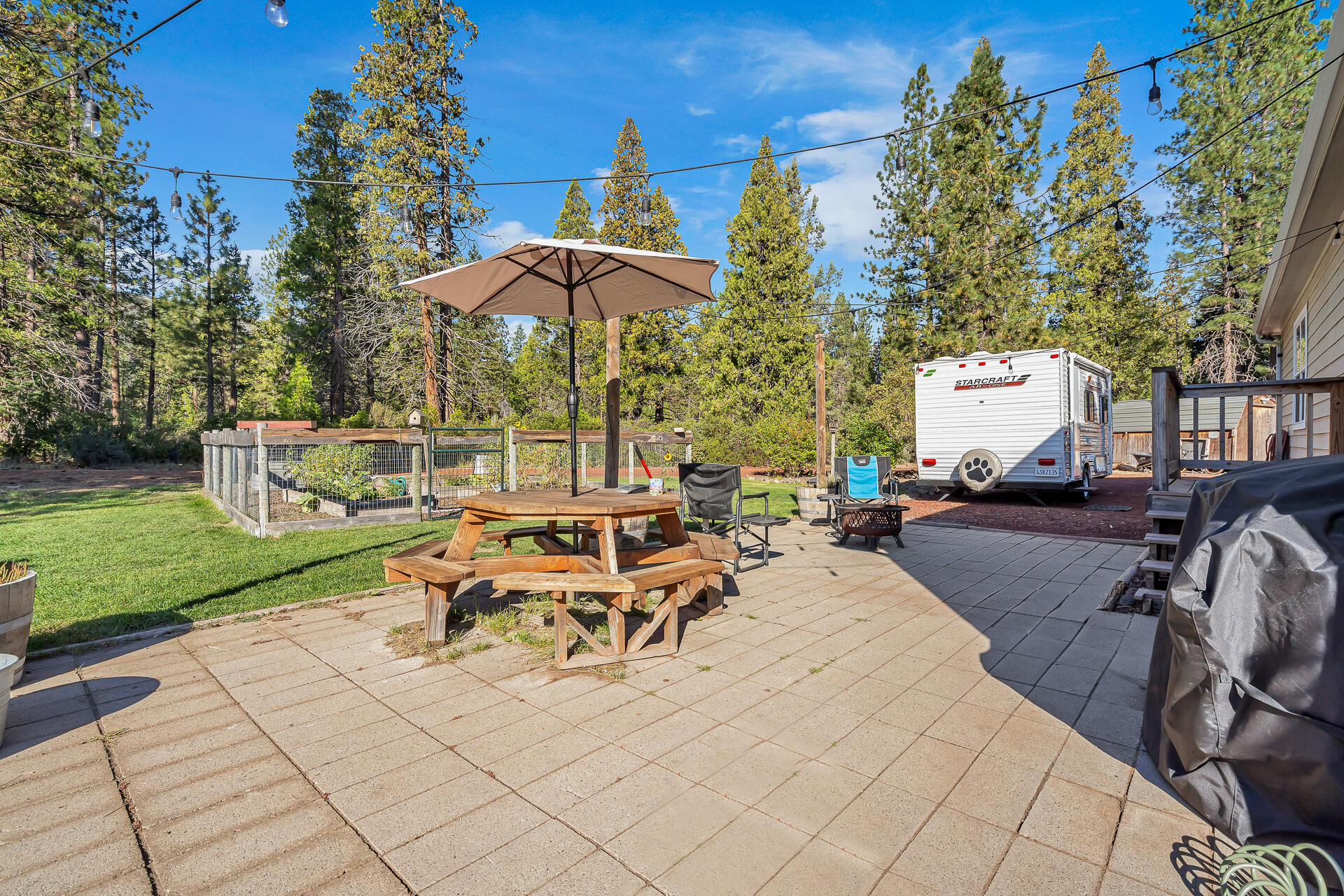 42048 Wilcox Road Hat Creek, CA 96040 - Photo 116 of 134 a view of a patio with table and chairs under an umbrella with large trees