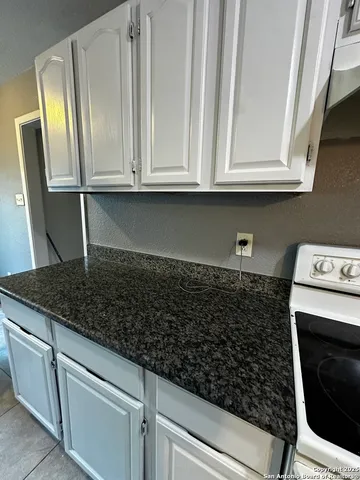 a kitchen with white cabinets and sink