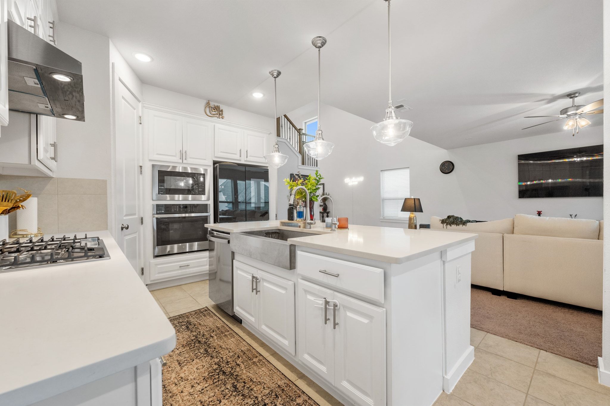 128 Three Oaks Lane Georgetown, TX 78628 - Photo 9 of 40 Kitchen with white cabinets, light tile patterned floors, appliances with stainless steel finishes, decorative light fixtures, and under cabinet range hood