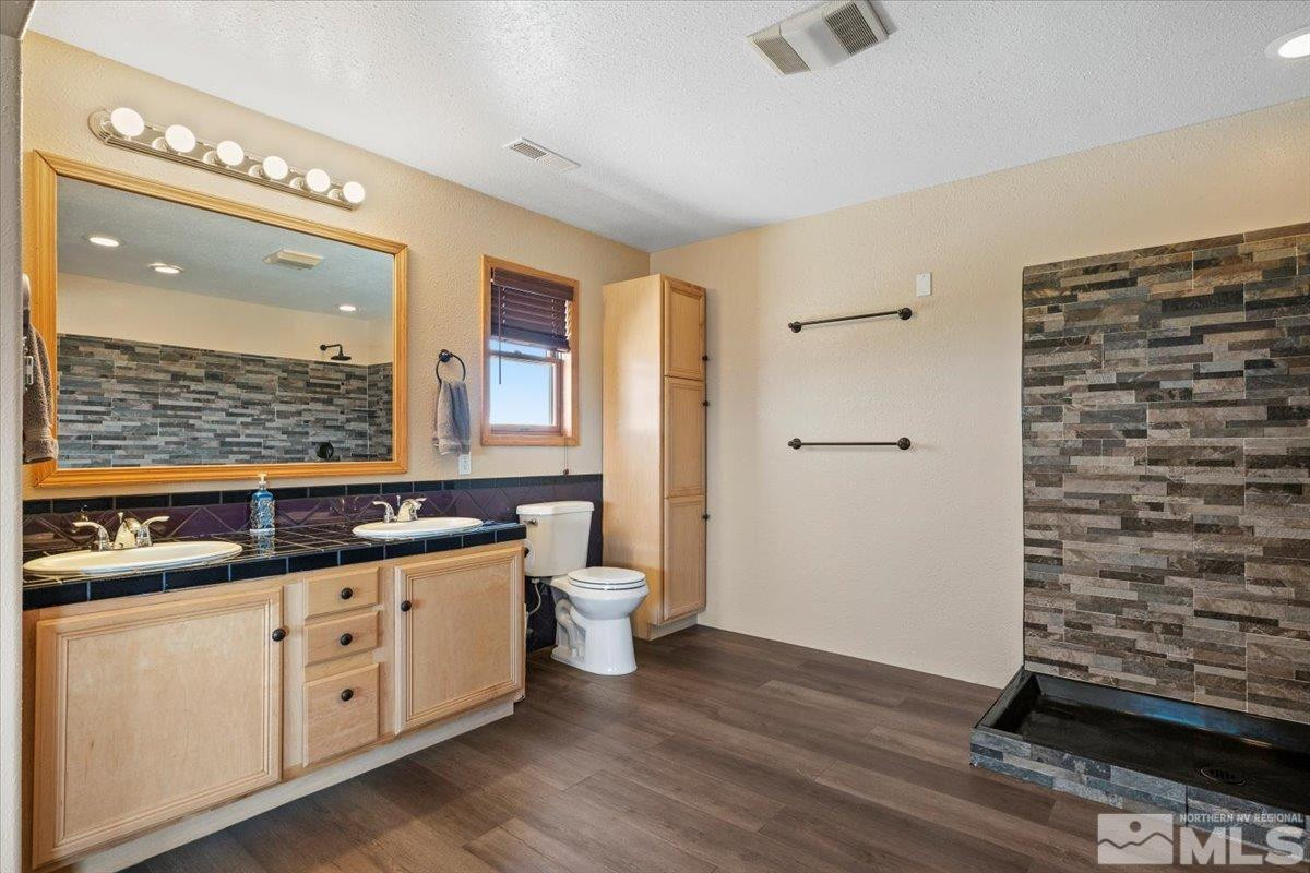 21470 Graves Road Reno, NV 89521 - Photo 11 of 37 a bathroom with a double vanity sink a mirror and a shower
