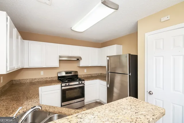 a kitchen with a refrigerator stove and white cabinets