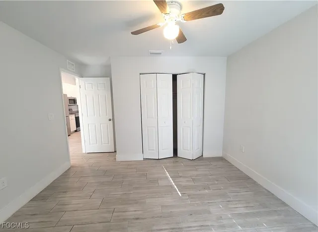 an empty room with wooden floor and chandelier fan