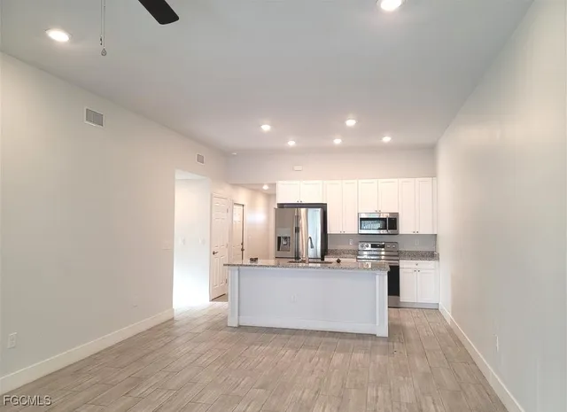 a large kitchen with a center island and stainless steel appliances