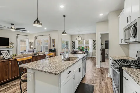 a kitchen with stainless steel appliances granite countertop a sink a stove and a wooden floors