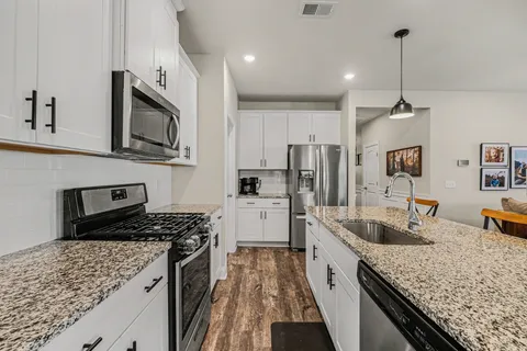 a kitchen with stainless steel appliances granite countertop a sink stove and refrigerator