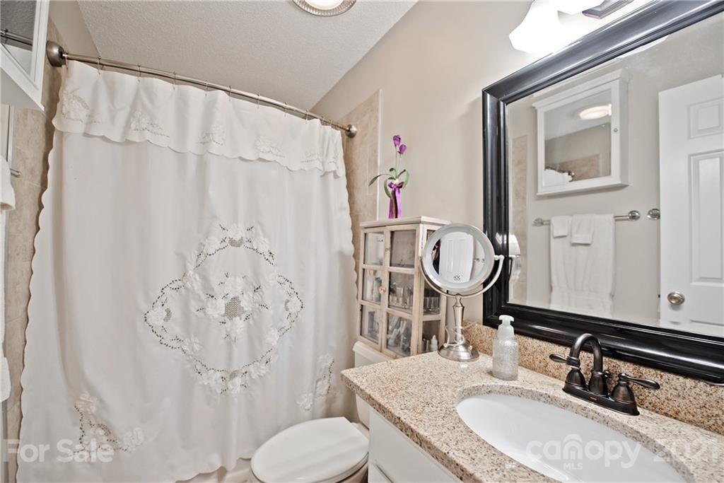 18809 Nautical Drive, Unit 302 Cornelius, NC 28031 - Photo 15 of 22 a bathroom with a granite countertop sink toilet and shower curtain