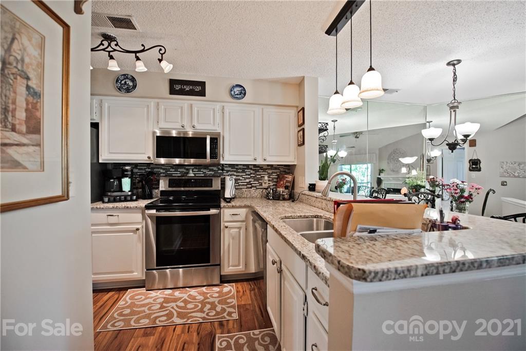18809 Nautical Drive, Unit 302 Cornelius, NC 28031 - Photo 6 of 22 a kitchen with granite countertop a sink a counter top space cabinets and stainless steel appliances