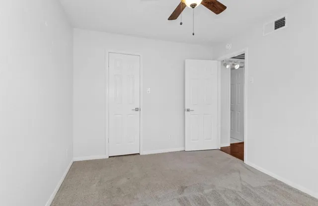 an empty room with chandelier fan and closet