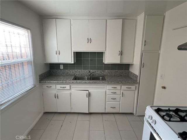 a kitchen with granite countertop white cabinets and white appliances