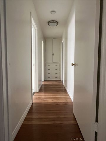 a view of a hallway with wooden floor and a bathroom