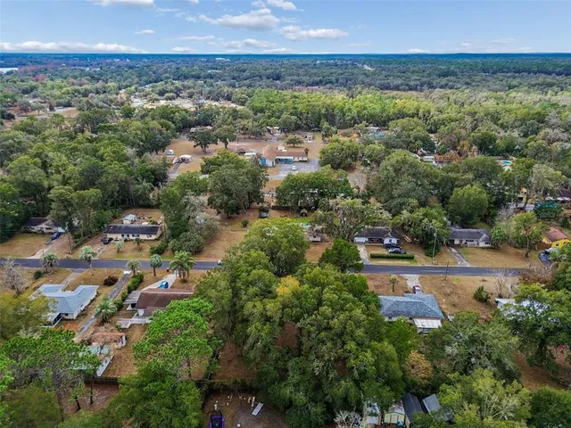 an aerial view of residential houses with outdoor space and trees
