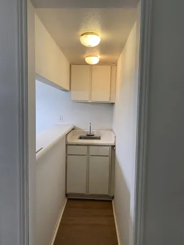 an empty room with wooden floor chandelier fan and windows