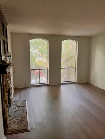 an empty room with wooden floor fan and windows