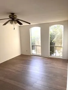 an empty room with wooden floor and windows