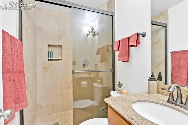 a bathroom with a granite countertop shower sink vanity and toilet