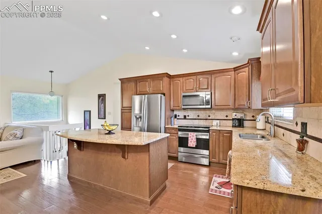 a kitchen with stainless steel appliances kitchen island granite countertop a sink stove and refrigerator