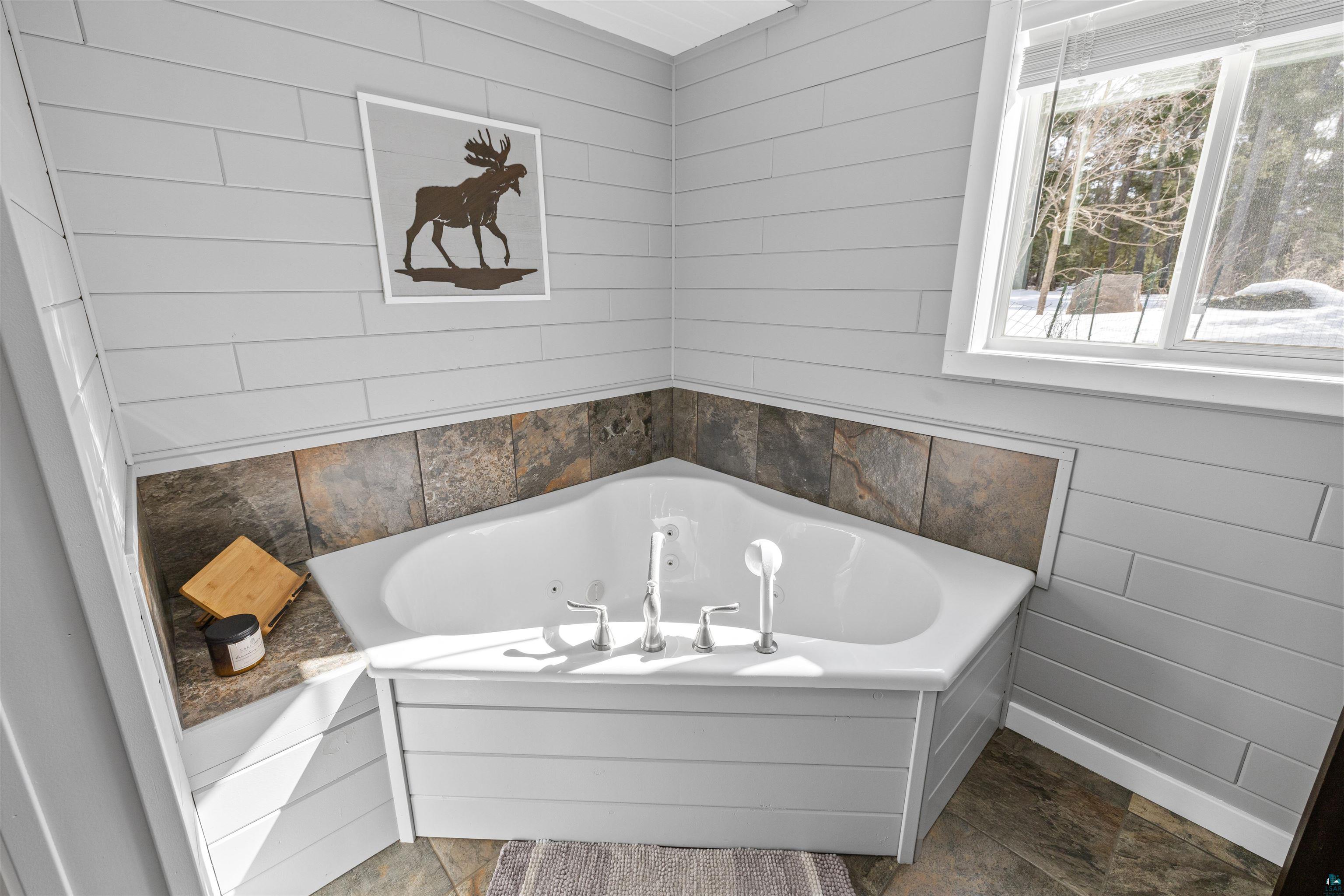 13462 Villa Road Ely, MN 55731 - Photo 23 of 68 Primary bathroom with a shower stall, tile flooring, vanity, a whirlpool tub, and wood walls
