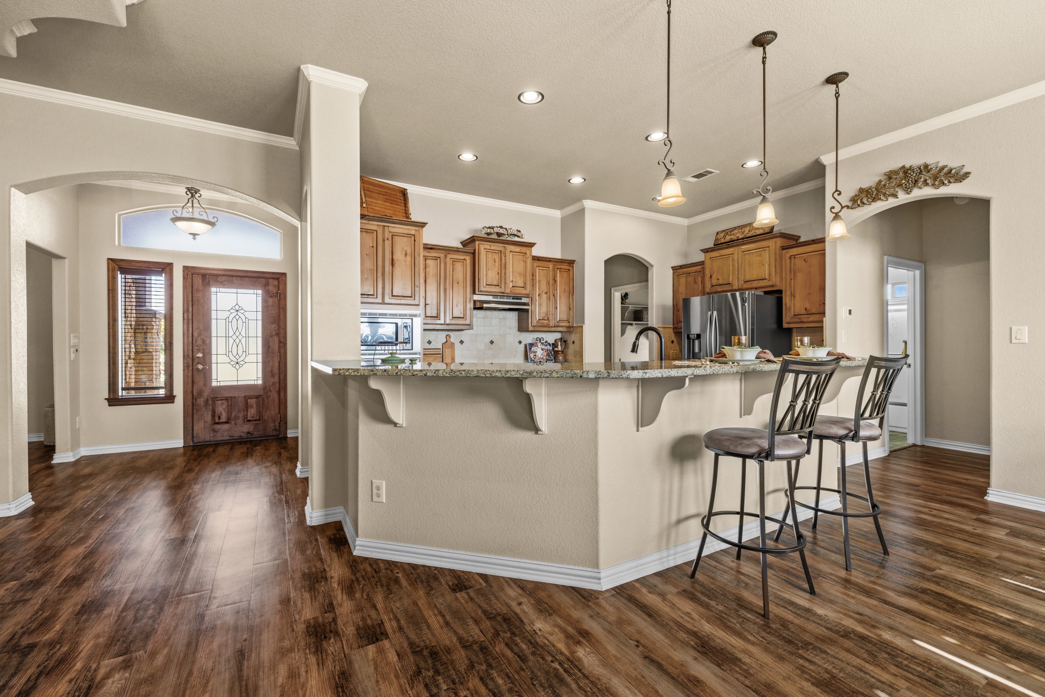 204 Skyline Road Georgetown, TX 78628 - Photo 15 of 40 Kitchen with arched walkways, a breakfast bar area, a spacious island, wood finish cabinets, and crown molding