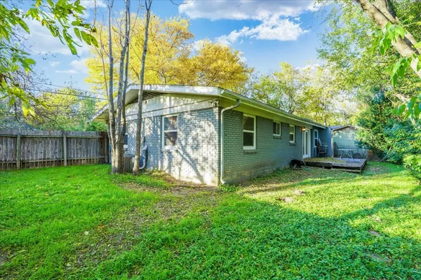 a view of a backyard with large trees and wooden fence