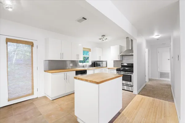 a kitchen with stainless steel appliances kitchen island wooden cabinets a sink a stove a refrigerator and island