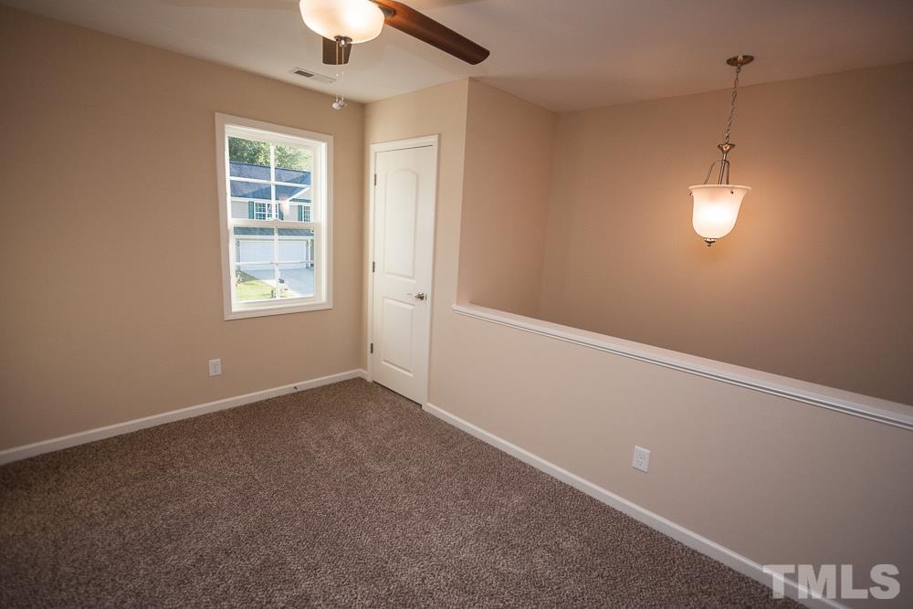 1856 Swepsonville Road Graham, NC 27253 - Photo 23 of 25 an empty room with a chandelier fan and windows