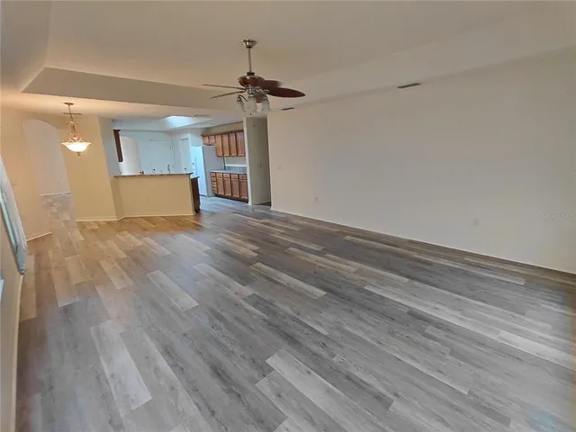 a view of empty room with wooden floor and ceiling fan